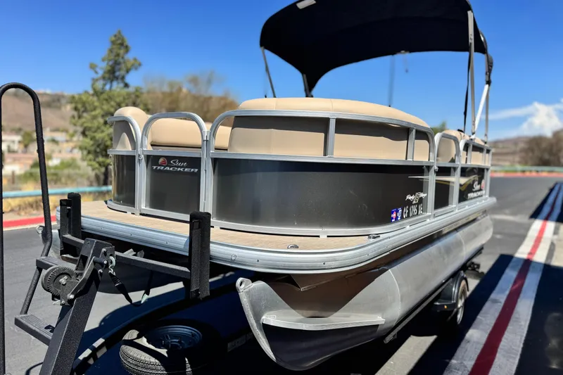 Slide: The Image of 2025 Sun Tracker Party Barge 16 DLX pontoon boat on trailer, sunny day. - 3