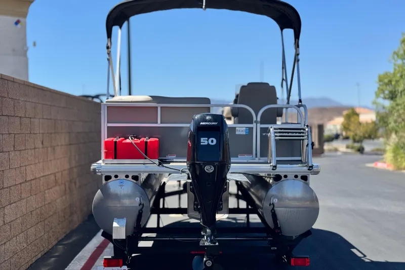 Slide: The Image of 2025 Sun Tracker Party Barge 16 DLX pontoon boat with Mercury 50 engine, parked outdoors. - 5