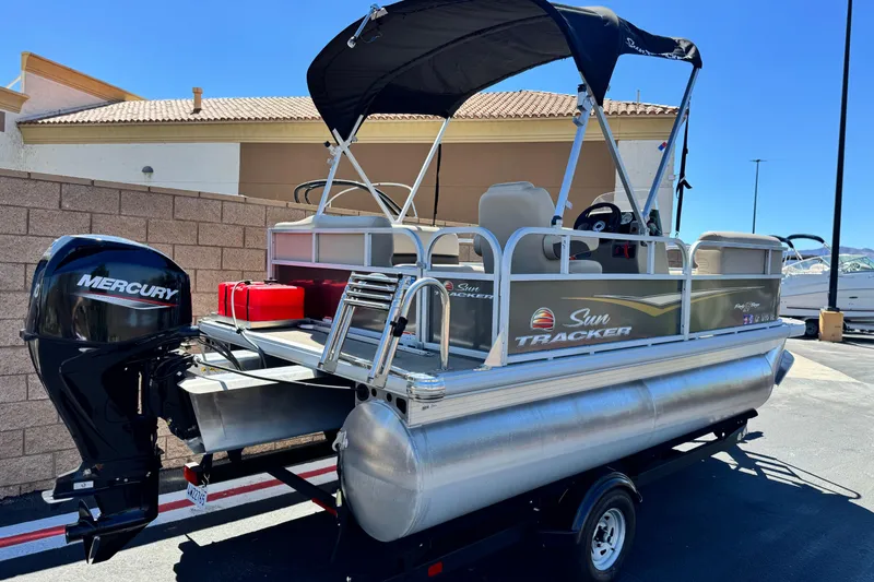 Slide: The Image of 2025 Sun Tracker Party Barge 16 DLX pontoon boat with Mercury engine, parked outdoors. - 6