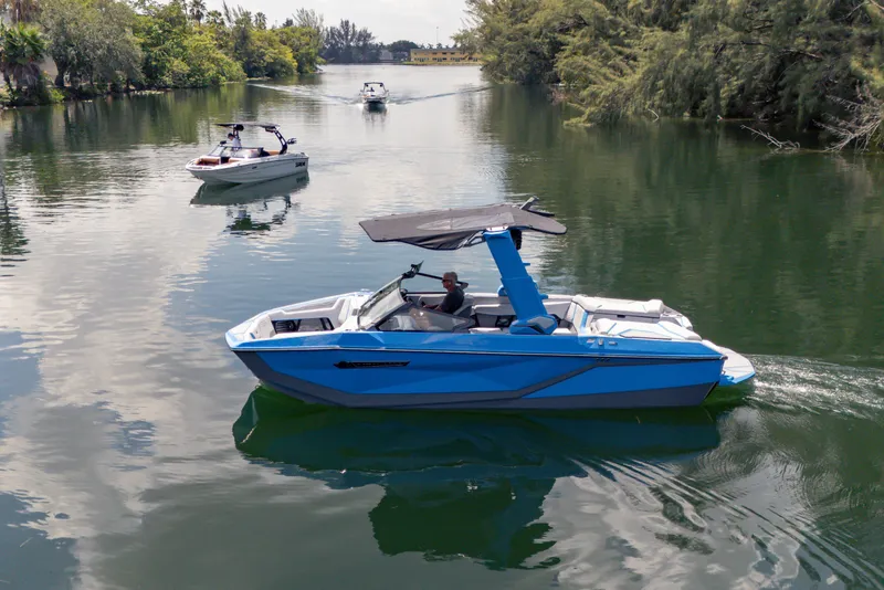 Slide: The Image of 2026 Nautique Super Air Nautique G23 boat cruising on a serene lake. - 25