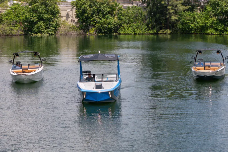 Slide: The Image of Three 2026 Nautique Super Air Nautique G23 boats on a serene lake. - 26