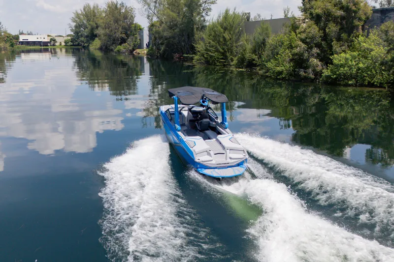 Slide: The Image of 2026 Nautique Super Air Nautique G23 cruising on a serene, tree-lined waterway. - 29