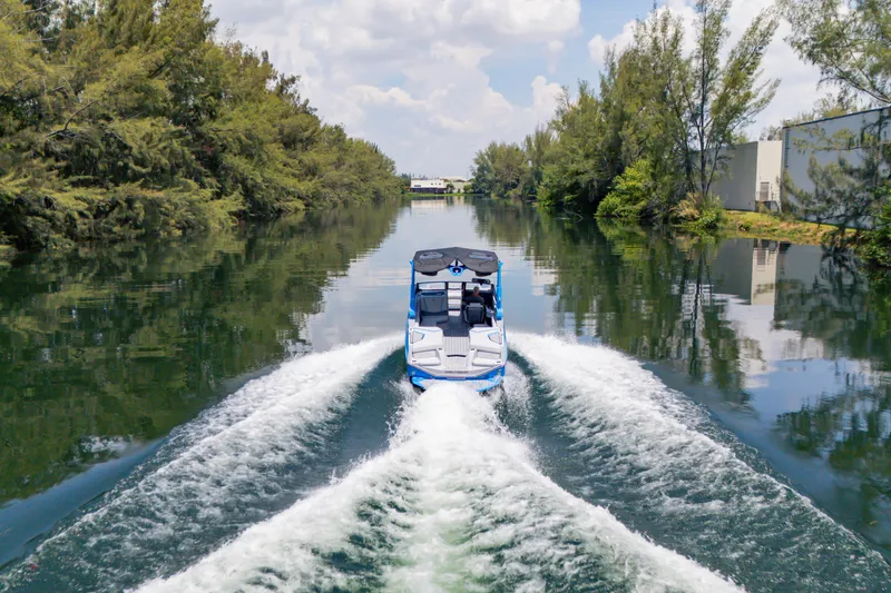 Slide: The Image of 2026 Nautique Super Air Nautique G23 cruising on a scenic, tree-lined waterway. - 32
