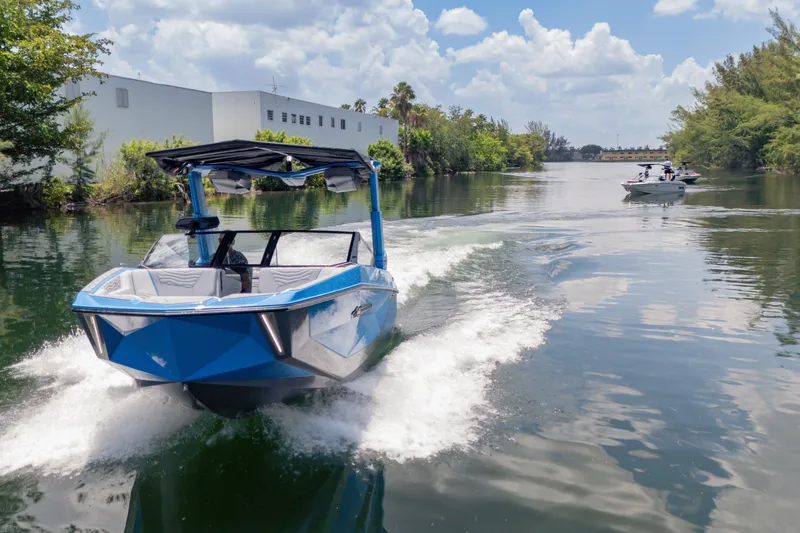 Slide: The Image of 2026 Nautique Super Air Nautique G23 cruising on a scenic waterway under a clear sky. - 37