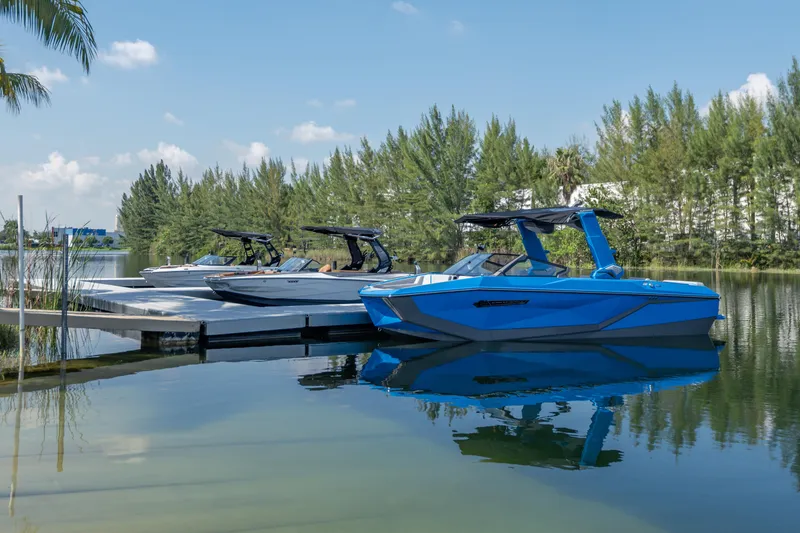 Slide: The Image of 2026 Nautique Super Air Nautique G23 boats docked on a serene lake. - 38