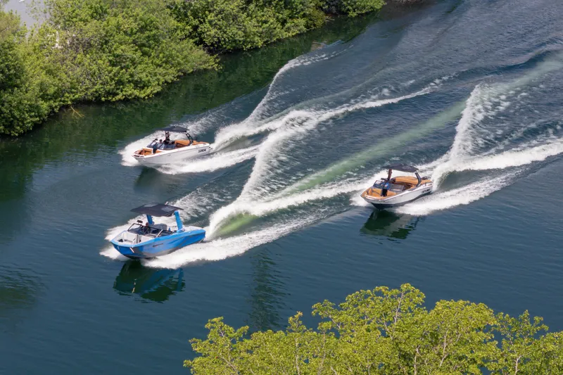 Slide: The Image of Three 2026 Nautique Super Air Nautique G23 boats cruising on a scenic waterway. - 42