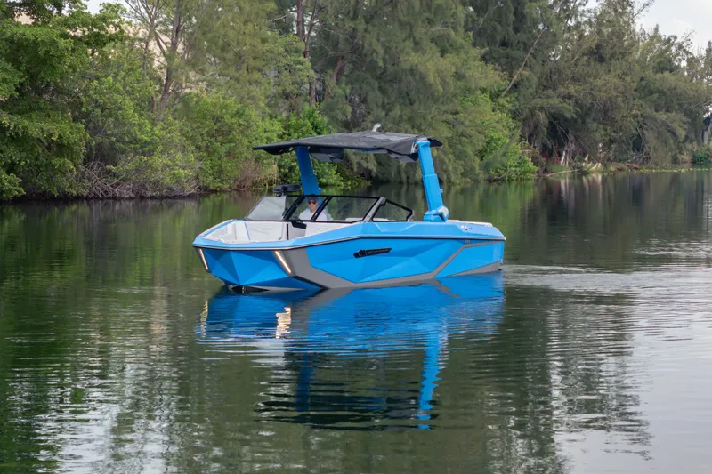 Slide: The Image of 2026 Nautique Super Air Nautique G23 boat on a serene lake, surrounded by lush greenery. - 43
