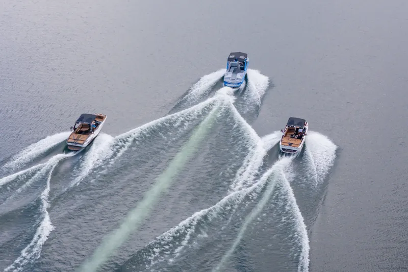 Slide: The Image of Three 2026 Nautique Super Air Nautique G23 boats creating wakes on open water. - 44