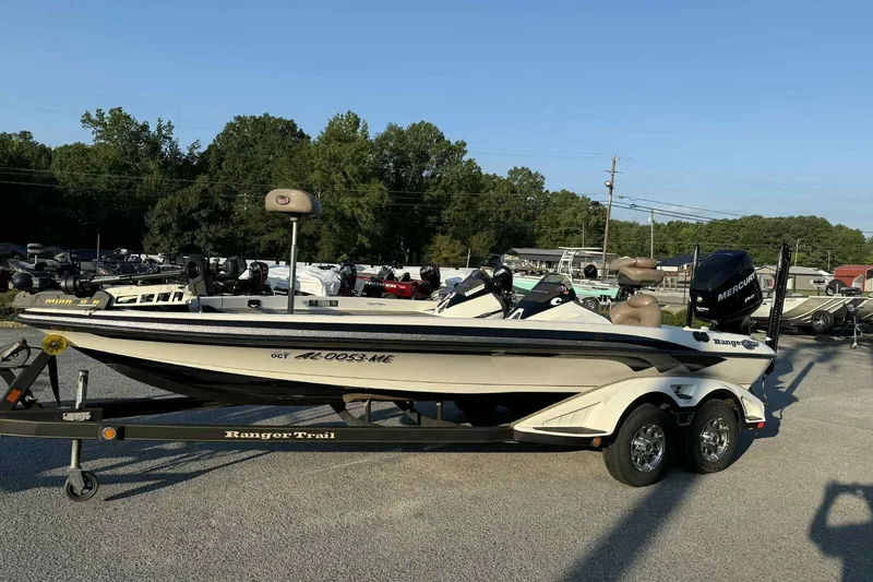 Slide: The Image of 2012 Ranger Z521 Comanche boat on trailer in outdoor lot, surrounded by trees and other boats. - 9
