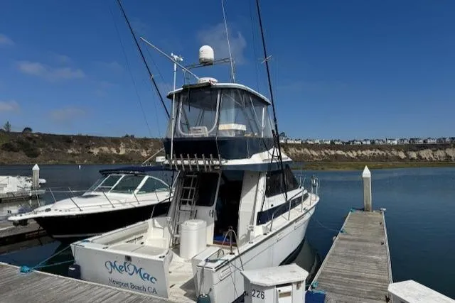 The Image of 1992 Mediterranean 38 Convertible yacht docked at marina under clear blue sky. - 0