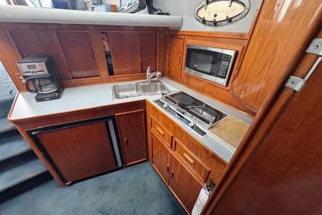 Slide: The Image of 1992 Mediterranean 38 Convertible yacht kitchen with microwave, stove, sink, and wooden cabinetry. - 13