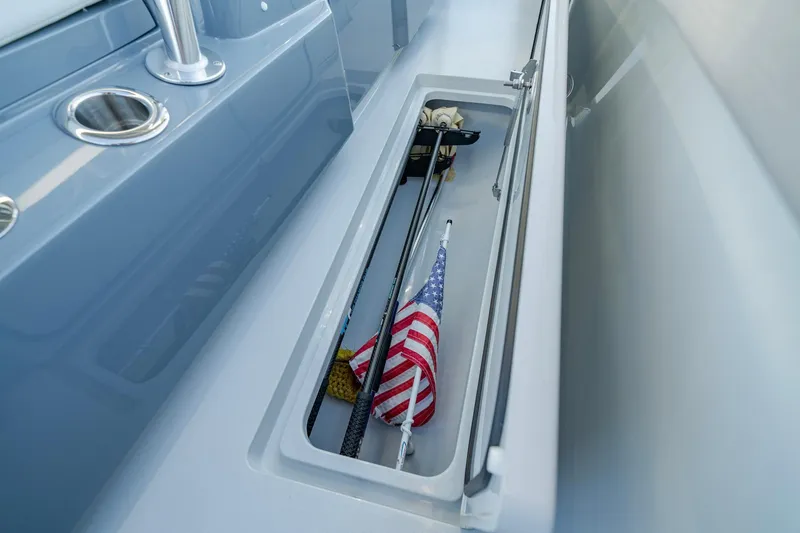 Slide: The Image of 2024 Valhalla V-29 Hybrid boat storage compartment with American flag and fishing rods. - 17