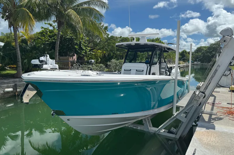 Slide: The Image of 2024 Blackfin 332 CC boat docked on a sunny day, surrounded by lush greenery. - 6