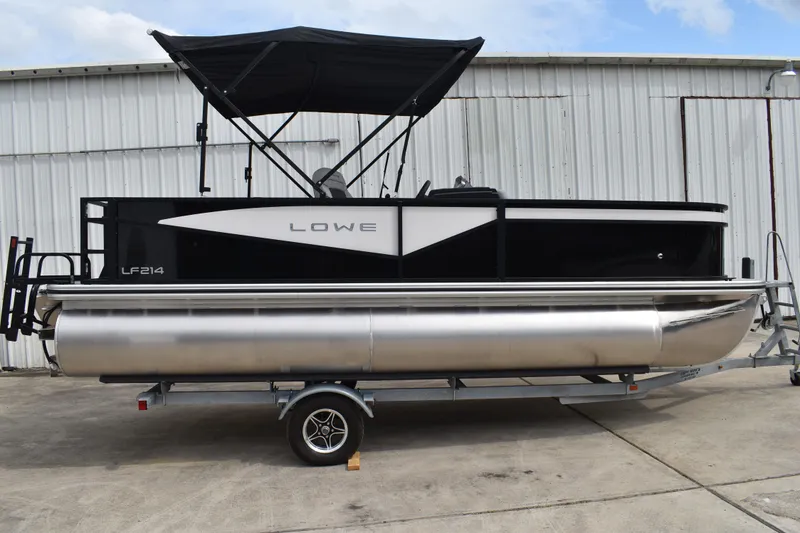 The Image of 2026 Lowe LF 214 pontoon boat on trailer, black and silver design, parked outdoors. - 0