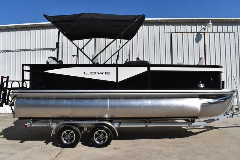 The Image of 2026 Lowe LF 214 pontoon boat with black canopy on trailer, parked outdoors. - 0