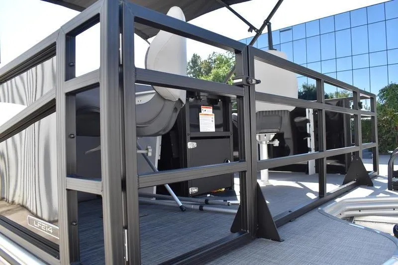 Slide: The Image of 2026 Lowe LF 214 pontoon boat with canopy, parked outdoors near a glass building. - 9