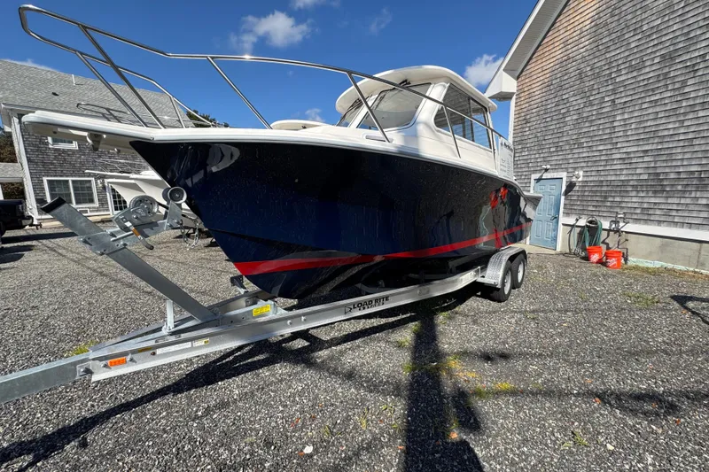 The Image of 2026 NorthCoast 235 HT boat on trailer, parked outside a building under a clear blue sky. - 0