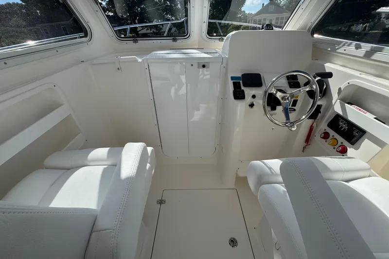 Slide: The Image of Interior of 2026 NorthCoast 235 HT boat with steering wheel and white seating. - 17