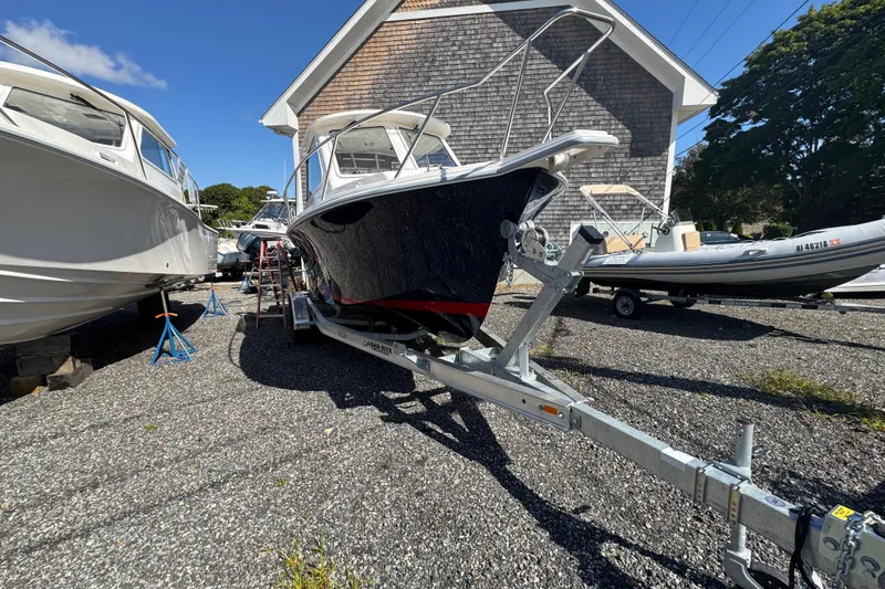 Slide: The Image of 2026 NorthCoast 235 HT boat on trailer, parked outdoors under clear blue sky. - 20