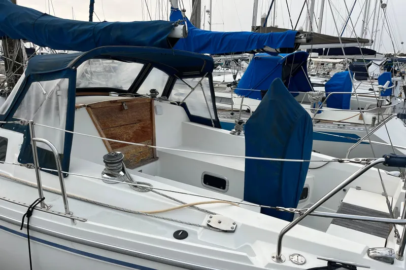 Slide: The Image of 1993 Catalina 36 sailboat docked in marina, featuring blue covers and wooden hatch. - 11