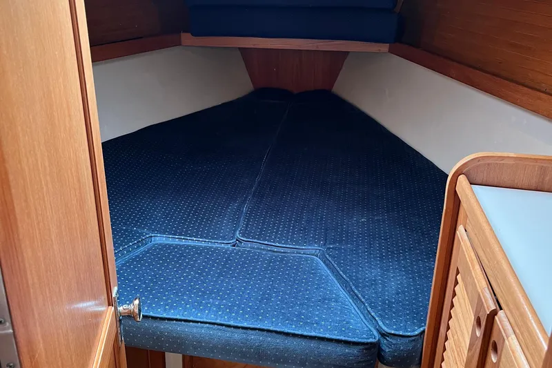 Slide: The Image of Interior cabin of a 1993 Catalina 36 sailboat with blue cushioned berth. - 26