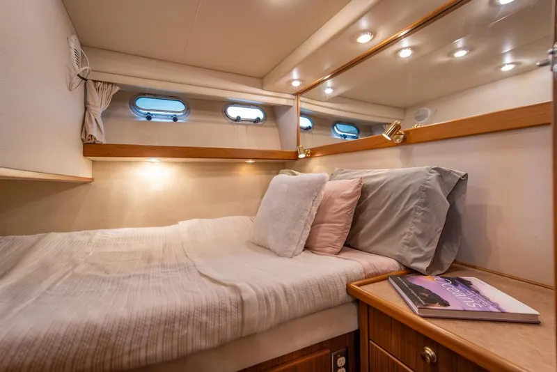 Slide: The Image of Cozy bedroom in 2000 Bayliner 4788 Pilot House Motoryacht with soft lighting and porthole windows. - 27