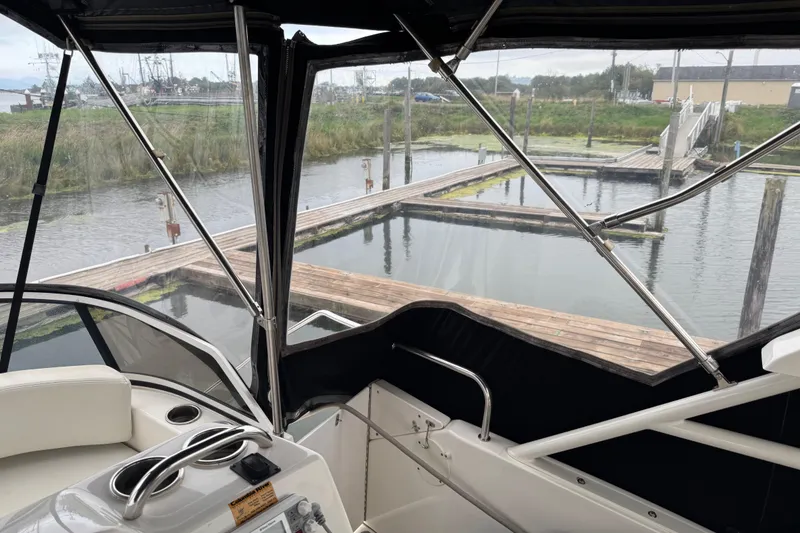 Slide: The Image of 2002 Silverton 352 Motor Yacht interior view at dock, featuring helm and seating area. - 24