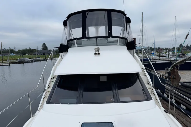 Slide: The Image of 2002 Silverton 352 Motor Yacht docked at marina, showcasing upper deck and windows. - 47