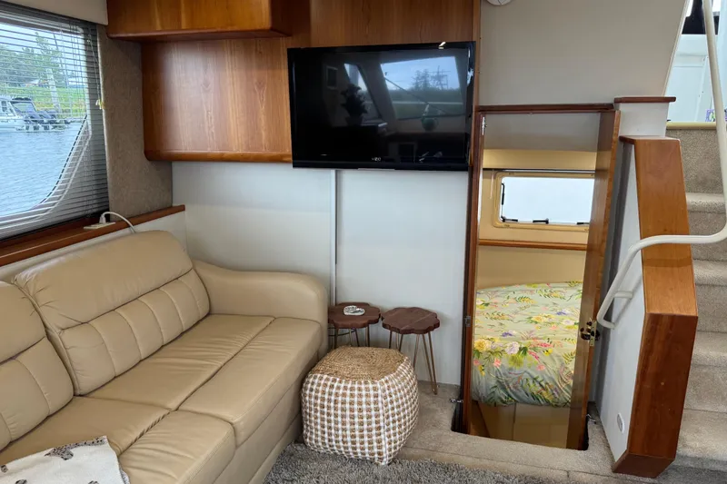 Slide: The Image of Interior of 2002 Silverton 352 Motor Yacht with beige sofa, TV, and cabin view. - 64
