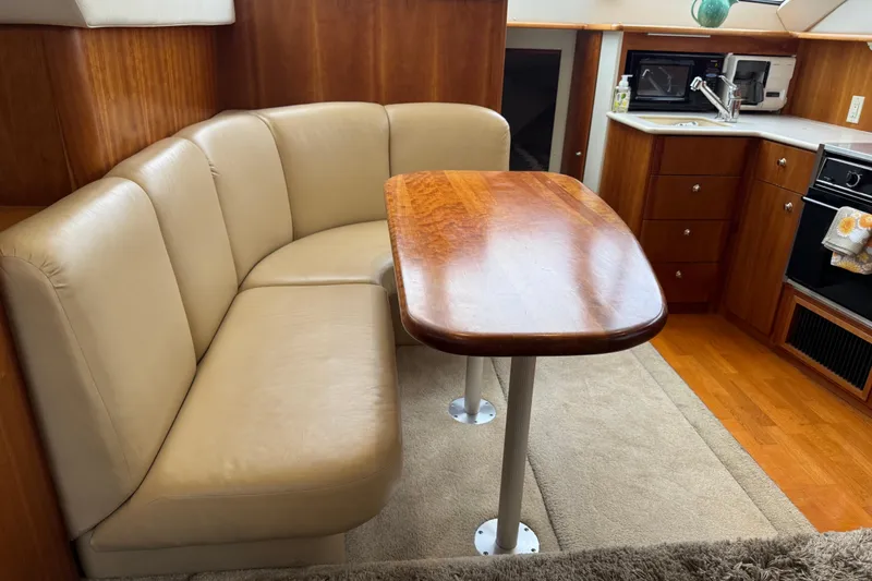 Slide: The Image of 2002 Silverton 352 Motor Yacht interior with beige seating and wooden dining table. - 70