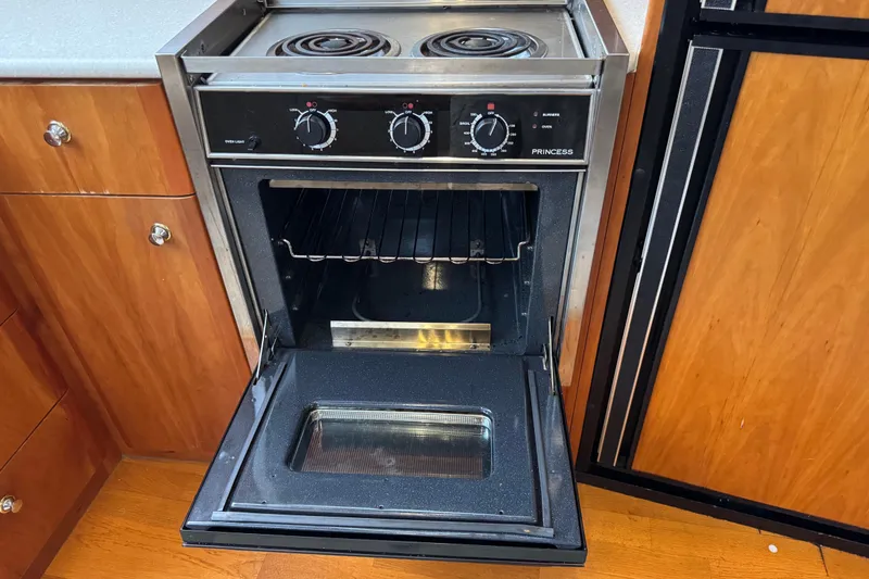 Slide: The Image of 2002 Silverton 352 Motor Yacht kitchen with open oven and stovetop. - 73