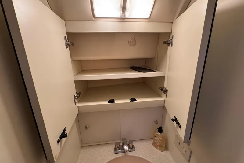 Slide: The Image of 2002 Silverton 352 Motor Yacht bathroom cabinet with open doors and sink. - 80