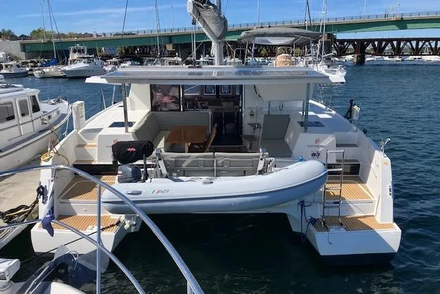 Slide: The Image of 2021 Fountaine Pajot Isla 40 catamaran docked at marina, featuring spacious deck and tender. - 33
