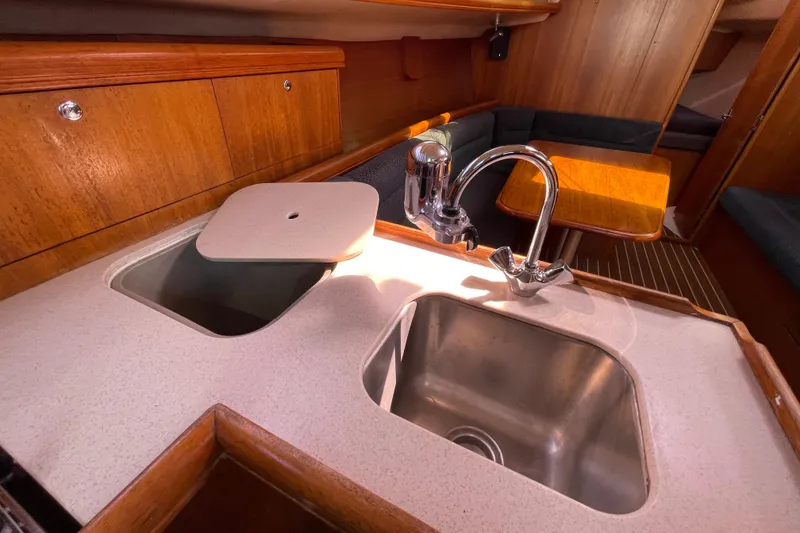 Slide: The Image of Hunter 33-2 yacht interior, 2004 model, featuring a compact kitchen sink and wooden cabinetry. - 17