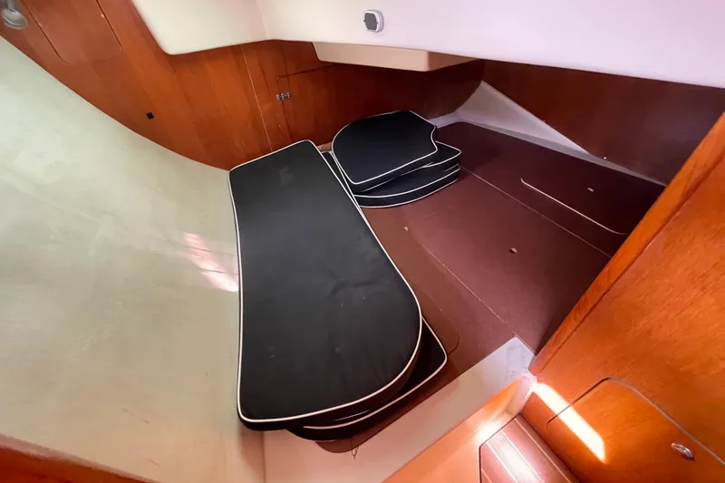 Slide: The Image of Interior cabin of a 2004 Hunter 33-2 sailboat with black cushions and wooden paneling. - 26