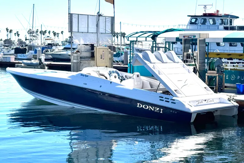 The Image of 2015 Donzi 38 ZR speedboat docked at marina, reflecting on calm water. - 0