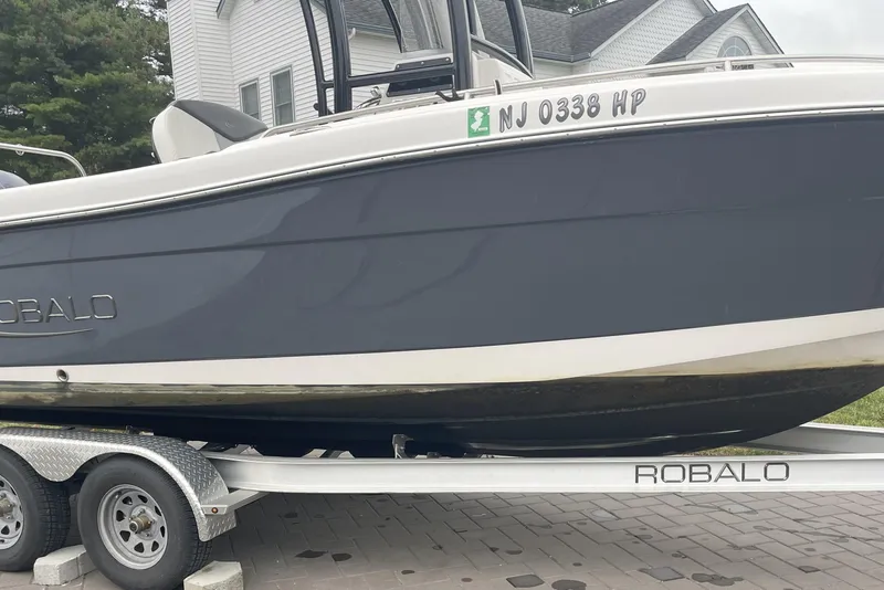 Slide: The Image of 2022 Robalo R222 Center Console boat on trailer, parked near a house. - 3