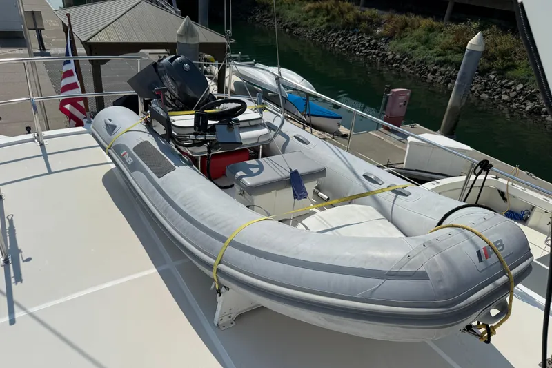 Slide: The Image of Inflatable boat on 1998 Kadey-Krogen 48' Northsea Widebody Pilothouse deck, docked by water. - 45