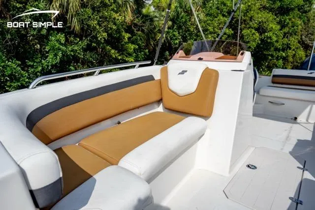 Slide: The Image of 2022 Starcraft SVX 191 OB boat interior with tan and white seating, lush greenery background. - 10