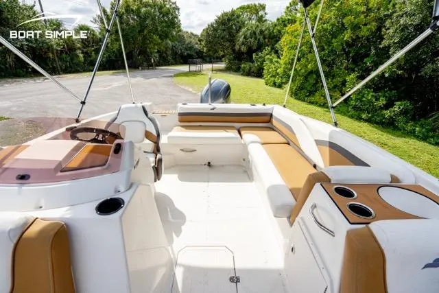 Slide: The Image of 2022 Starcraft SVX 191 OB boat interior with tan and white seating, cup holders, and lush greenery. - 11