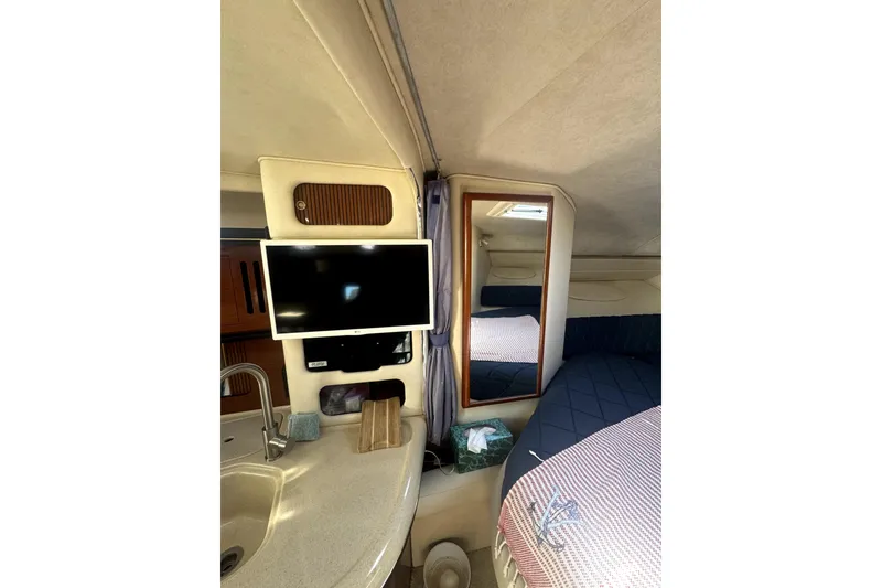 Slide: The Image of 2002 Sea Ray 340 Sundancer cabin interior with TV, mirror, and cozy bedding. - 11