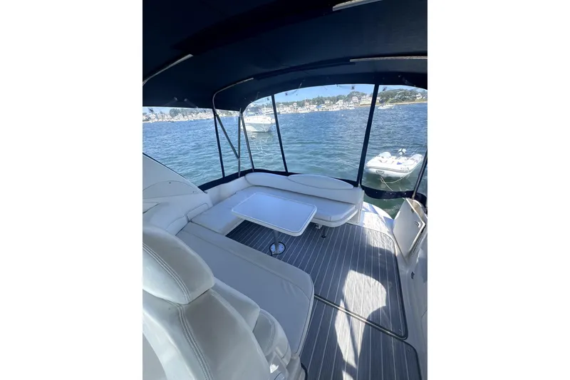 Slide: The Image of 2002 Sea Ray 340 Sundancer boat interior with seating and table, overlooking calm waters. - 2