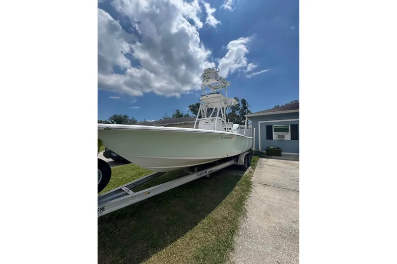 Slide: The Image of 2016 Sea Hunt BX 24 BR boat on trailer, parked beside a house under a cloudy sky. - 2