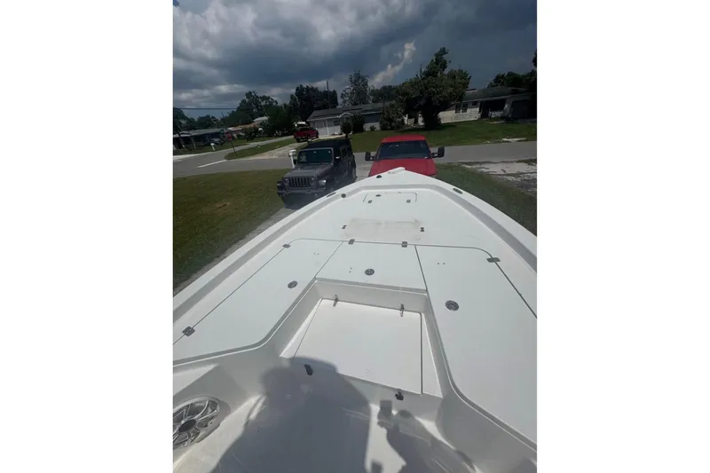 Slide: The Image of 2016 Sea Hunt BX 24 BR boat on trailer, parked near vehicles under cloudy sky. - 8