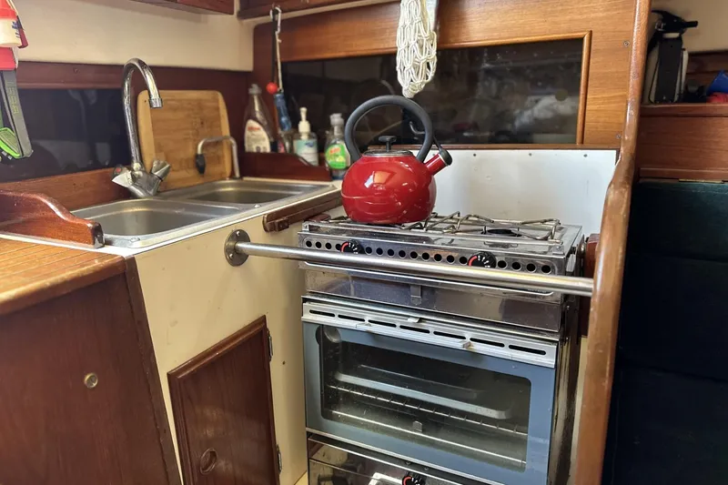 Slide: The Image of Compact kitchen in a 1982 Cape Dory 30 sailboat with stove and red kettle. - 12