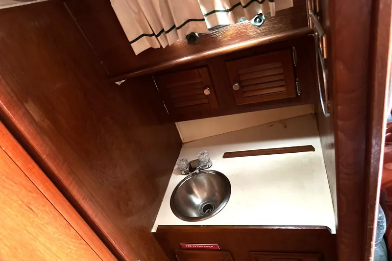 Slide: The Image of 1982 Cape Dory 30 yacht interior with wooden cabinetry and compact sink area. - 15