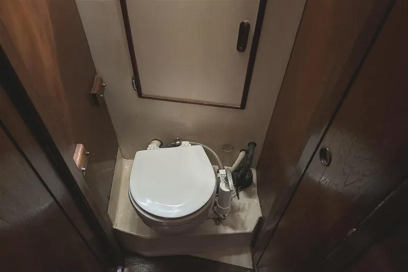 Slide: The Image of 1982 Cape Dory 30 boat bathroom with compact marine toilet and wooden cabinetry. - 16