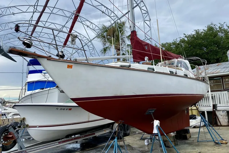 Slide: The Image of 1982 Cape Dory 30 sailboat on stands, with red hull and white deck, in a boatyard. - 21