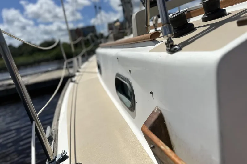 Slide: The Image of 1982 Cape Dory 30 sailboat deck with rigging, docked under a sunny sky. - 32