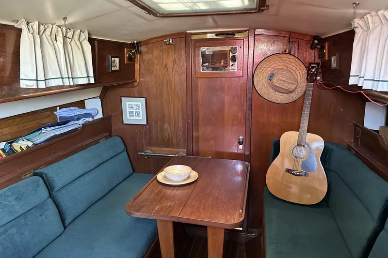 Slide: The Image of Cozy 1982 Cape Dory 30 sailboat interior with wooden table, guitar, and teal seating. - 7